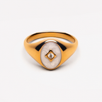 Gold-tone oval signet ring with white inset and clear stone, unbranded