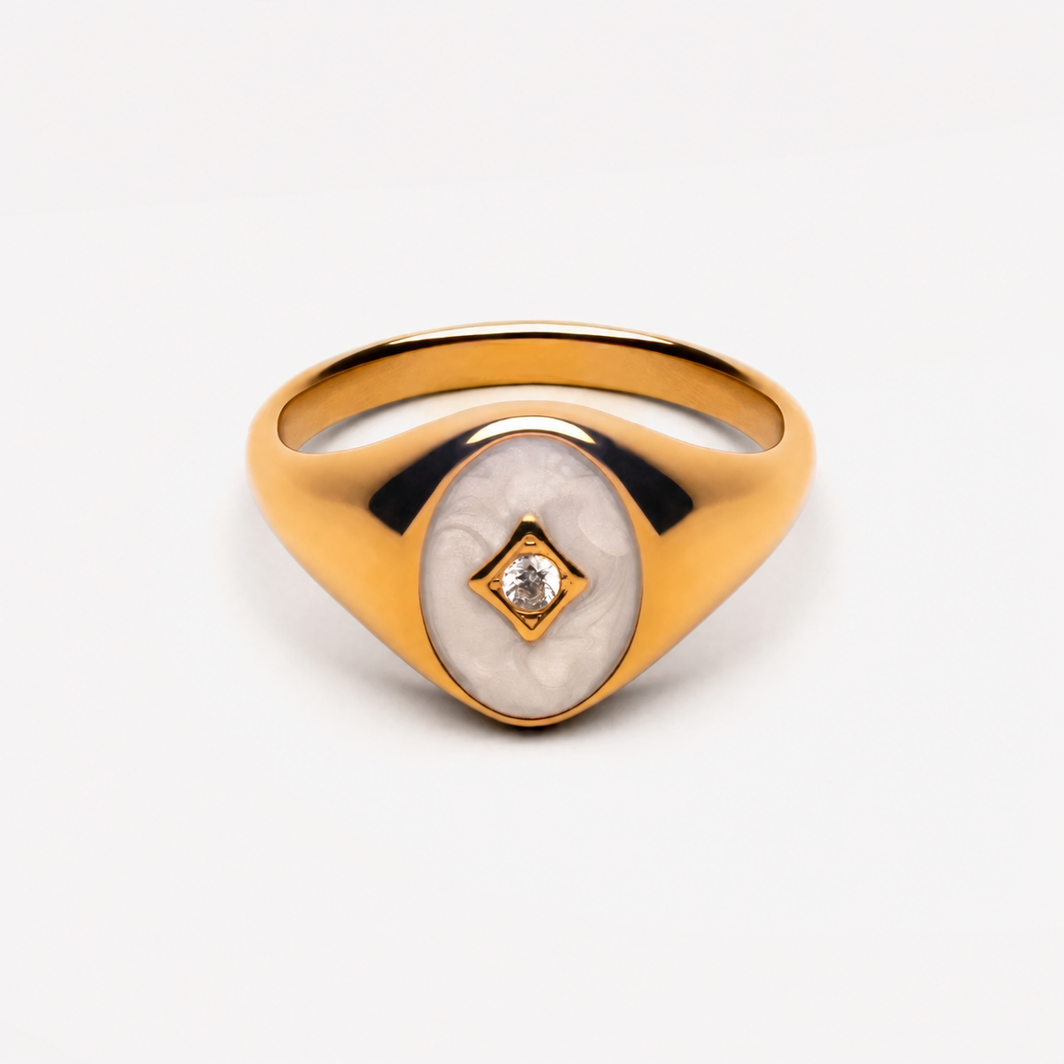 Gold-tone oval signet ring with white inset and clear stone, unbranded