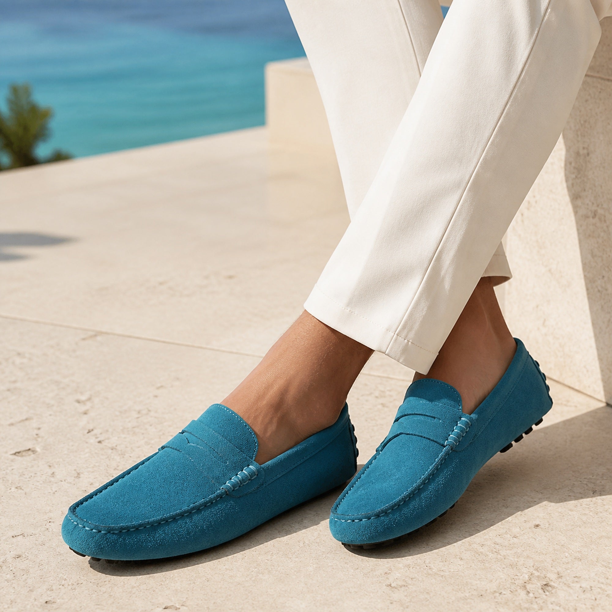 Man wearing Averino teal penny driver loafers at a coastal resort