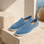 Marivon sapphire-blue boat loafers on travertine, editorial product scene