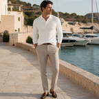 Man wearing the white Rovevello polo on a Mediterranean marina promenade