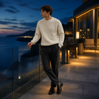 Man wearing the white Urevento sweater on a coastal rooftop at blue hour