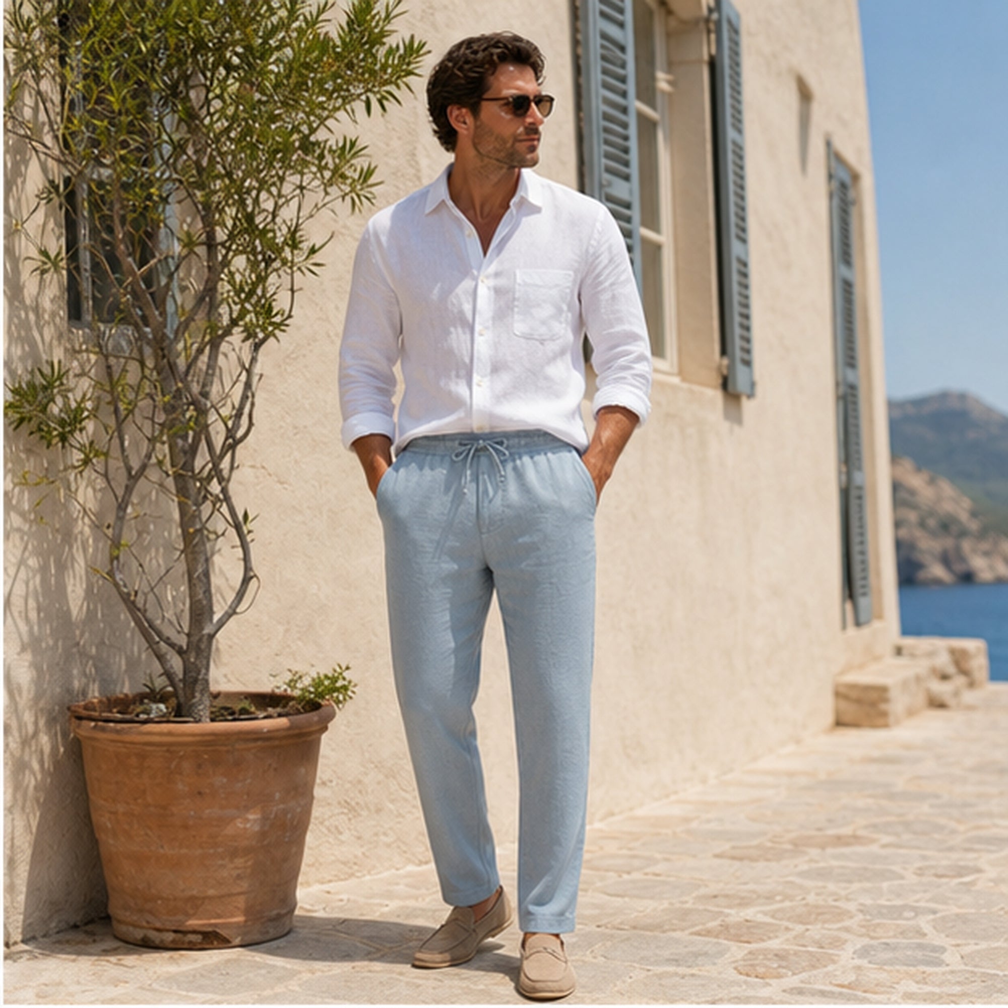 Light blue Xaverel linen trousers styled beside a coastal villa